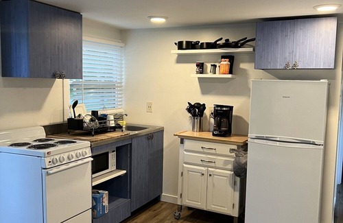 Inglis Apartment | Step into this cozy 2-bedroom cabin nestled in the tranquil woods. The main living area offers comfy seating, including a pull-out futon for additional sleeping space. An efficiency kitchen awaits your culinary adventures, equipped with essentials fo