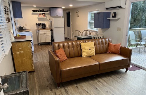 Inglis Apartment | Step into this cozy 2-bedroom cabin nestled in the tranquil woods. The main living area offers comfy seating, including a pull-out futon for additional sleeping space. An efficiency kitchen awaits your culinary adventures, equipped with essentials fo