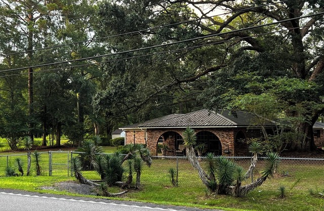 Large fenced in home under a giant, moss covered, southern oak tree.