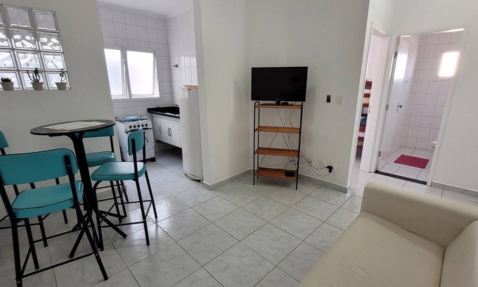 Mongagua Apartment | Apartamento moderninho, com sacada de frente para o mar. Sala bem iluminada.