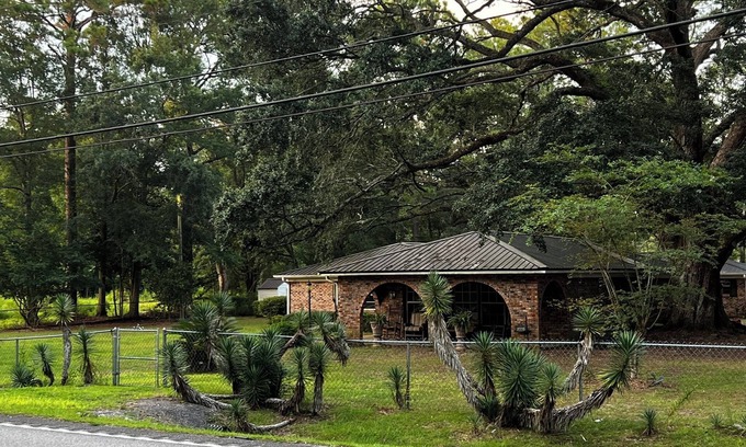 Moss Point House | Large fenced in home under a giant, moss covered, southern oak tree.